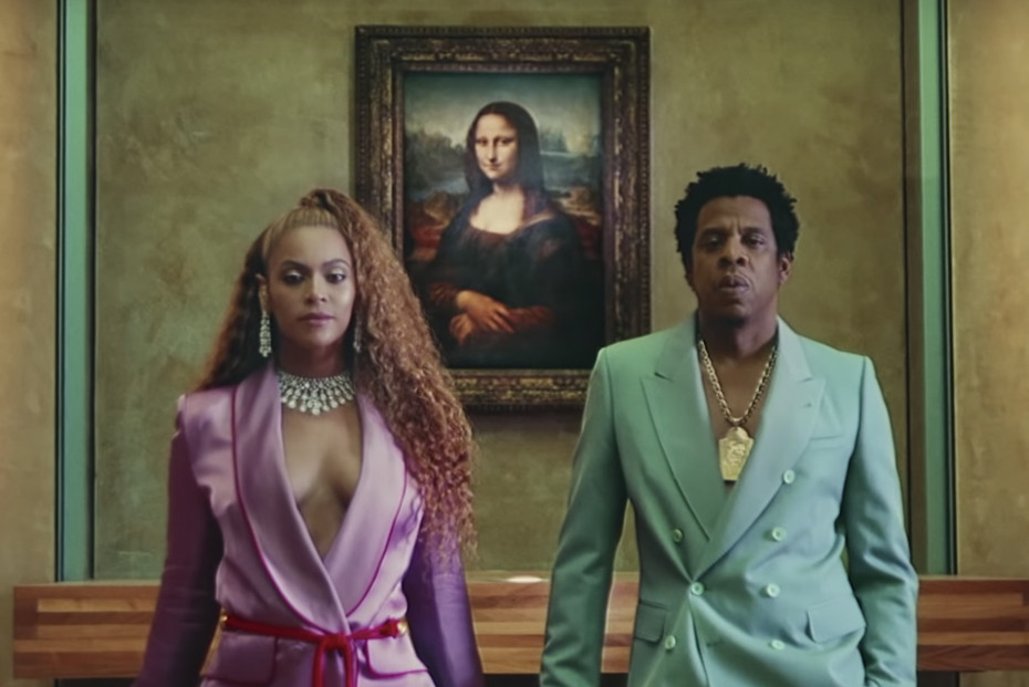 Beyonce and Jay-Z wearing pastel suits in front of Mona Lisa painting.